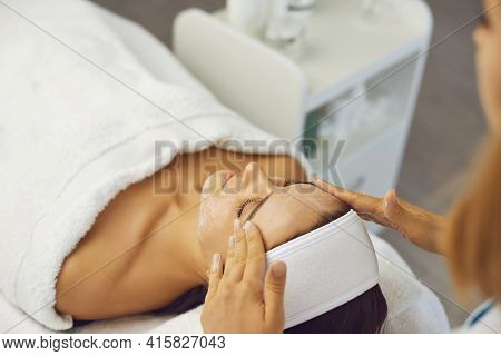Hands Of Cosmetologist Making Facial Massage With Cream For Woman In Beauty Salon