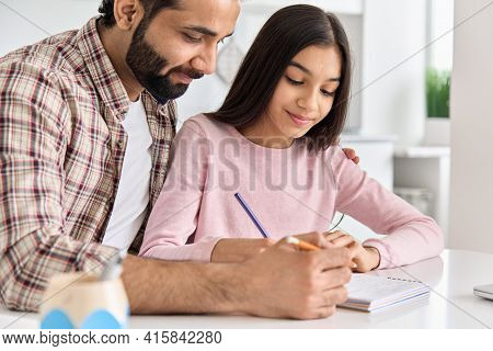 Happy Indian Father Helping School Child Teen Daughter Studying At Home. Young Caring Dad Explaining