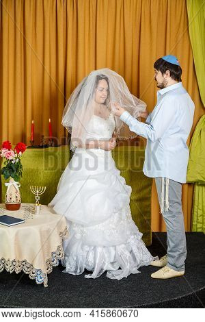 During The Chuppah Ceremony At A Synagogue Wedding, The Groom Covers The Bride With A Veil In The Ba