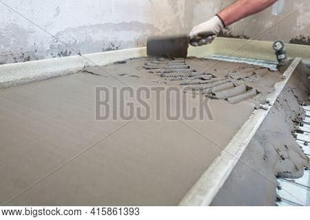 Construction Worker Performs Floor Screed Indoors. Leveling The Floor.