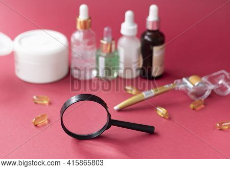Magnifying Glass Against The Background Of Blurred Face Serums And Dermoroller
