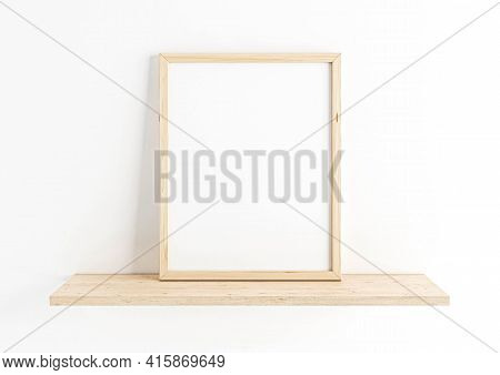 Single 8x10 Vertical Wooden Frame Mockup On Wooden Shelf And White Wall. One Empty Poster Frame Mock