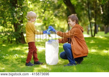 Woman Volunteer And Little Boy Picking Up The Plastic Garbage And Putting It In Biodegradable Trash-