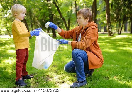 Woman Volunteer And Little Boy Picking Up The Plastic Garbage And Putting It In Biodegradable Trash-