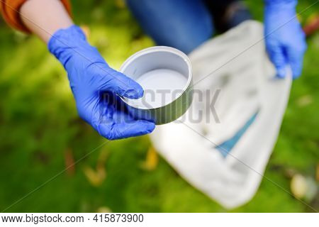 Volunteer Picking Up The Plastic Garbage And Putting It In Biodegradable Trash-bag On Outdoors. Ecol