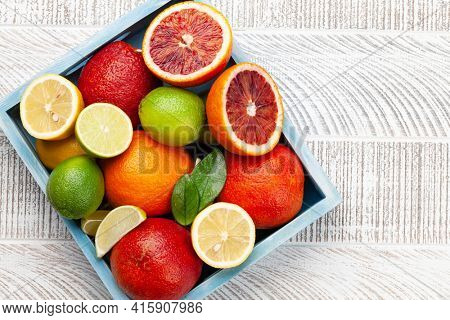 Various fresh citrus fruits in wooden box. Bood orange, lime, lemon. Top view flat lay with copy space