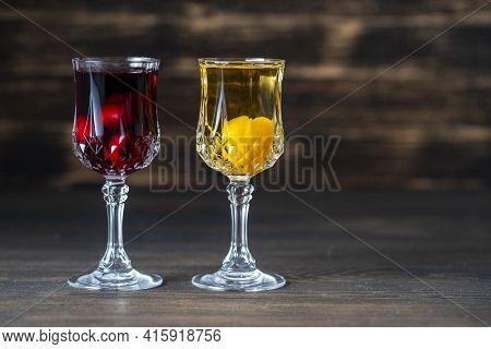 Homemade Tincture Of Red Cherry And Yellow Cherry Plum In A Wine Crystal Glasses On Wooden Backgroun