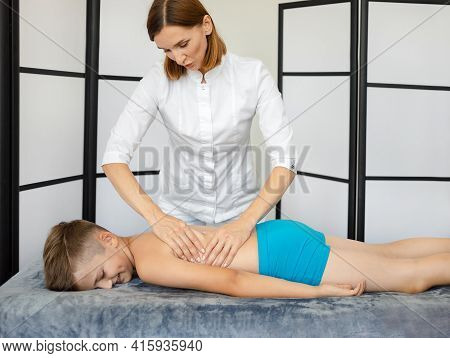 Woman Reflexologist, Masseur Makes A Massage To A Child In The Clinic. Massage Room.