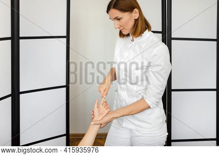 Reflexologist European Woman At The Medical Center Massages The Patients Hand, Gently Affecting The 