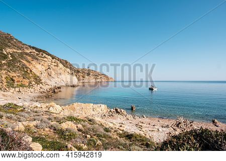 A Sailing Yacht Is Moored In A Bay On The Translucent Mediterranean Sea On The Coast Of La Revellata
