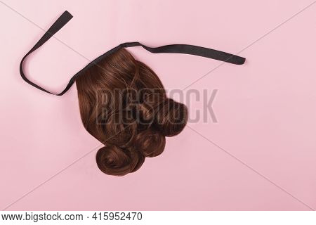 A Brown Hairpiece On The Pink Background. Flat-lay.
