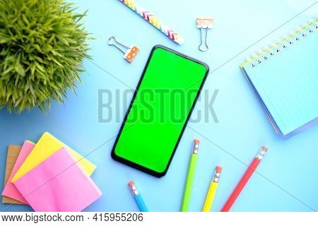 Top View Of Man Hand Using Smart Phone With Stationary On Blue Background
