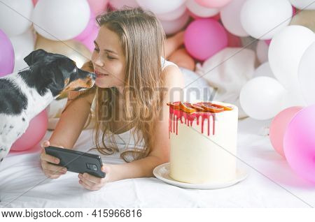 Lovely Lady In Pajama Making Selfie In Her Bedroom Using Phone And Play With Her Dog. Indoor Portrai