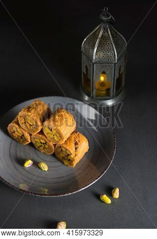 Rolls of baked baklava with Ramadan lamp at the background. Islamic Festive food recipes.  