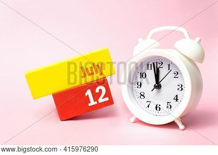 July 12nd. Day 12 Of Month, Calendar Date. White Alarm Clock On Pastel Pink Background. Summer Month