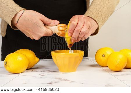 Woman Squeezing A Half Lemon With A Wooden Squizzer