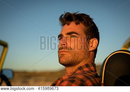 Portrait of caucasian man watching sunset in beach baggy. beach break on summer holiday road trip.