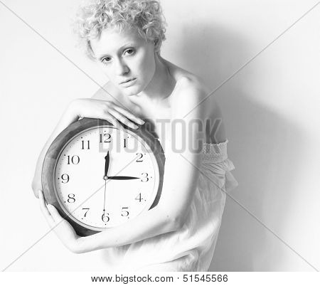 Scrawny girl with big clock in hands, b/w photo.