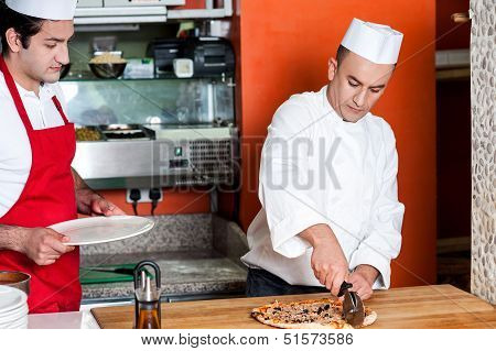 Chef Cutting Pizza Into Pieces