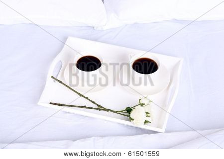 Cups of coffee on comfortable soft bed with pillows