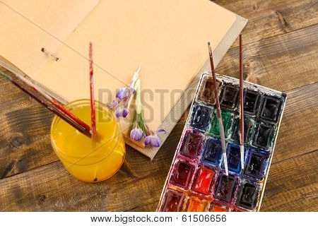 Composition with colorful watercolors, brushes and sketcher on wooden background 
