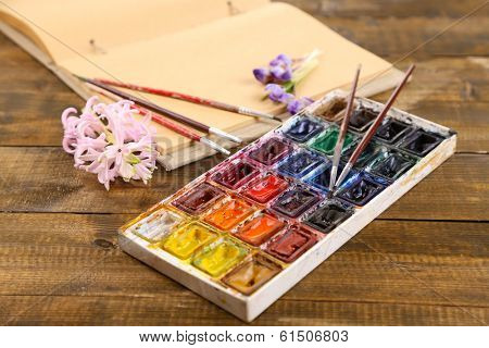 Composition with colorful watercolors, brushes and sketcher on wooden background 