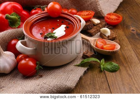 Tasty tomato soup and vegetables on wooden table
