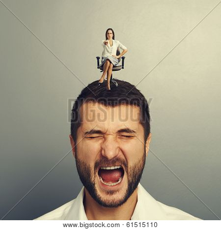 earnest woman sitting on the discontented man and pointing 