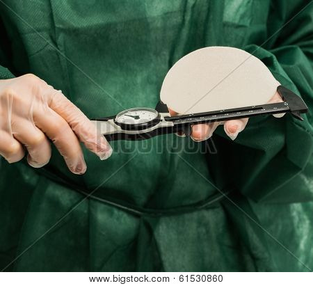 Plastic surgeon hands measuring silicon breast implants with calliper 