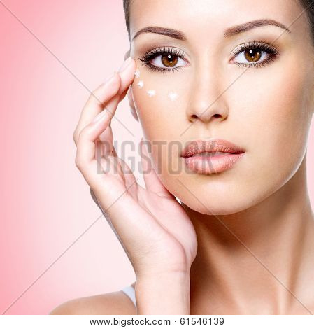 Woman With Healthy Face Applying Cosmetic Cream Under The Eyes