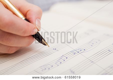 Hand with pen and music sheet