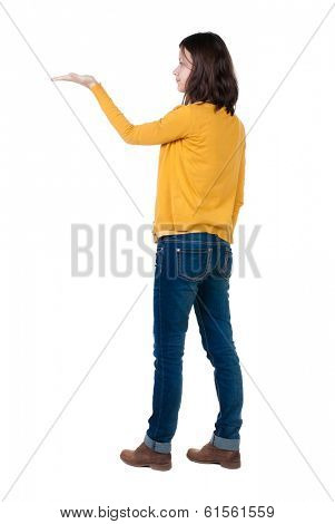 Back view of Beautiful business woman in yellow pulover looking at wall and Holds a hand up.  young brunette girl standing. Rear view people. Isolated over white background. 