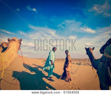 Vintage retro hipster style travel image ofvintage retro hipster style travel image of Rajasthan travel background - two indian cameleers (camel drivers) with camels.  Thar desert,  Rajasthan, India