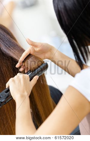 Backview of hair stylist doing hair style for woman in hairdressing salon. Concept of fashion and beauty