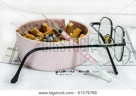 Ashtray, Syringe, Glasses And Other Stress Object From Work On White Blueprint Background
