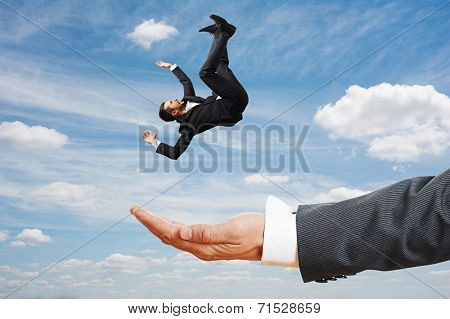 big palm catching small frightened businessman over blue sky