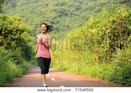 young fitness woman running at forest trail
