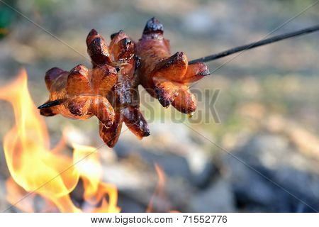 Roasting sausages over a fire in the wild grilled sausages