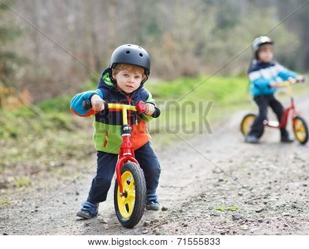Two Active Little Sibling Boys Having Fun On Bikes In Forest