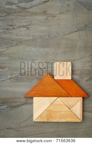abstract picture of a house built from seven tangram wooden pieces against slate rock background, a traditional Chinese puzzle game, the artwork copyright by the photographer