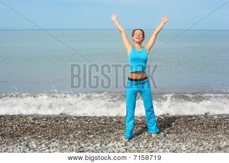 donna che indossa clothers sportivo con le mani sollevate sulla costa del Mar
