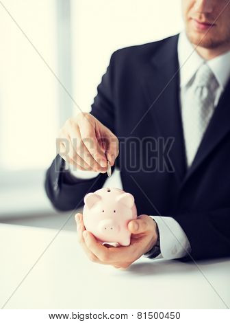 picture of man putting coin into small piggy bank