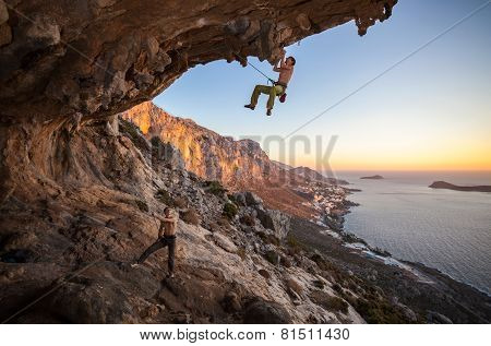 Male rock climber climbing on a roof in a cave