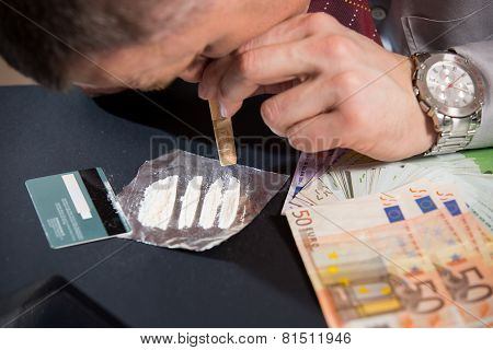 Young man preparing cocaine for sniffing using a credit card.