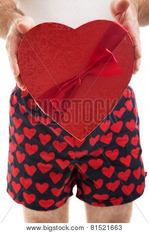 Guy in his heart boxer shorts giving a valentines day box of chocolates to you.,  