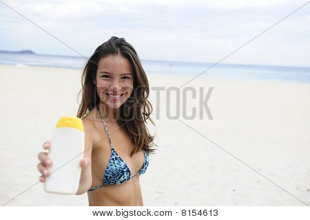 Žena ukazuje Suncream na pláži