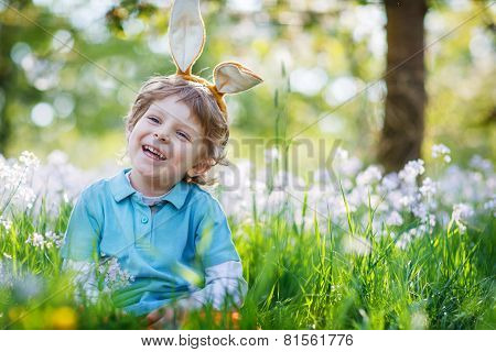 Cute Happy Little Boy Wearing Easter Bunny Ears At Spring Green Grass