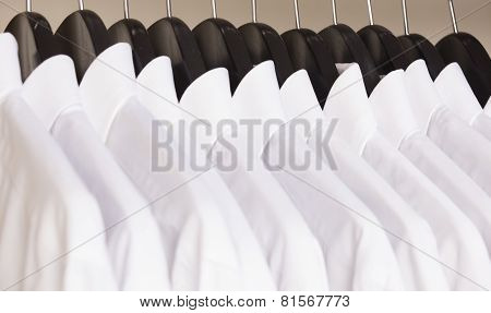 row of cloth hangers with white shirts