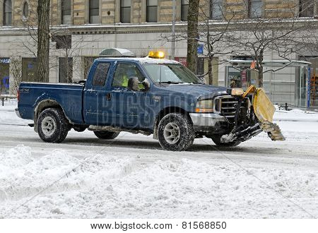 Truck with snowplow clearing street after snowstorm