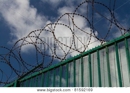 Razor Wire On Top Of Green Fence Guarding French Ferry Terminal.